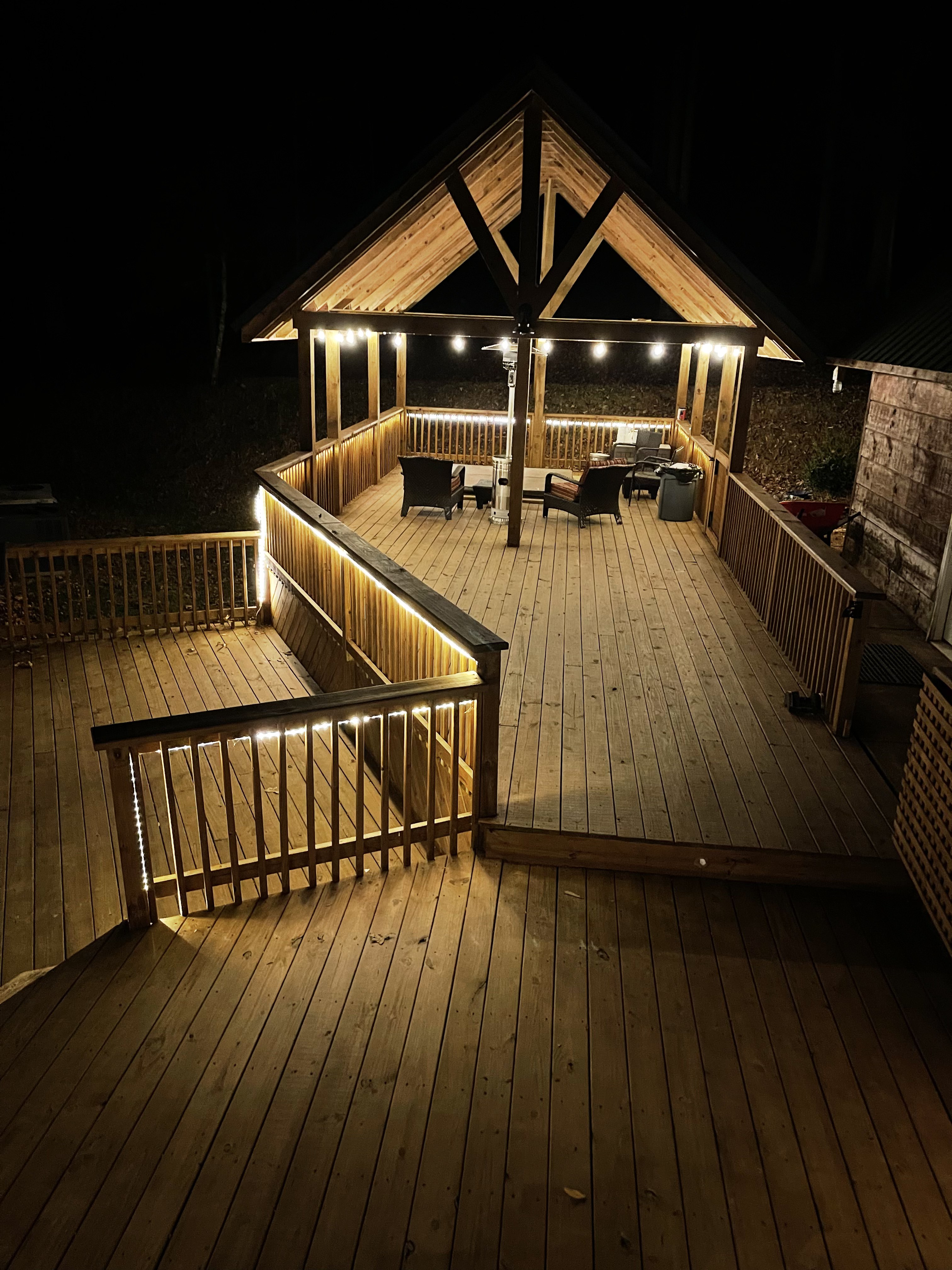 Covered pavilion at night, string lights and heat lamp warming the seating area