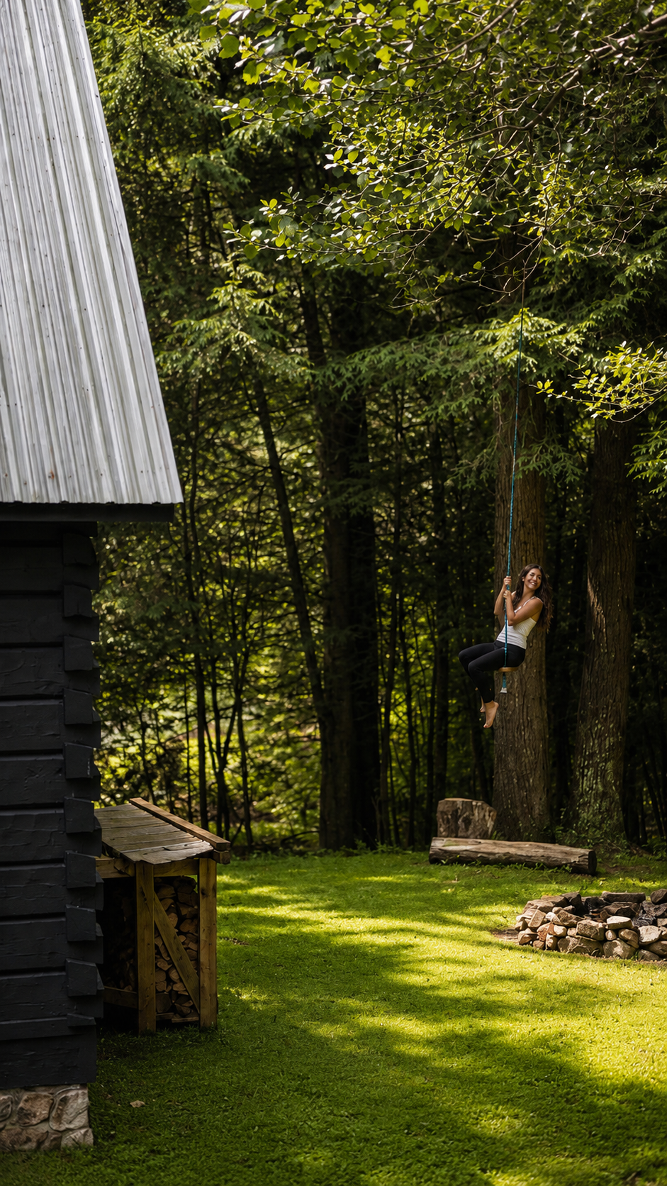 Guest riding the property zip line at the edge of the wooded yard