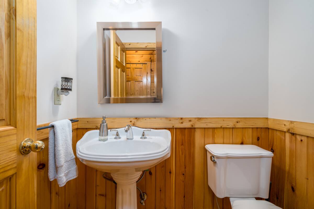 Half bath with pedestal sink, pine wainscoting and framed mirror