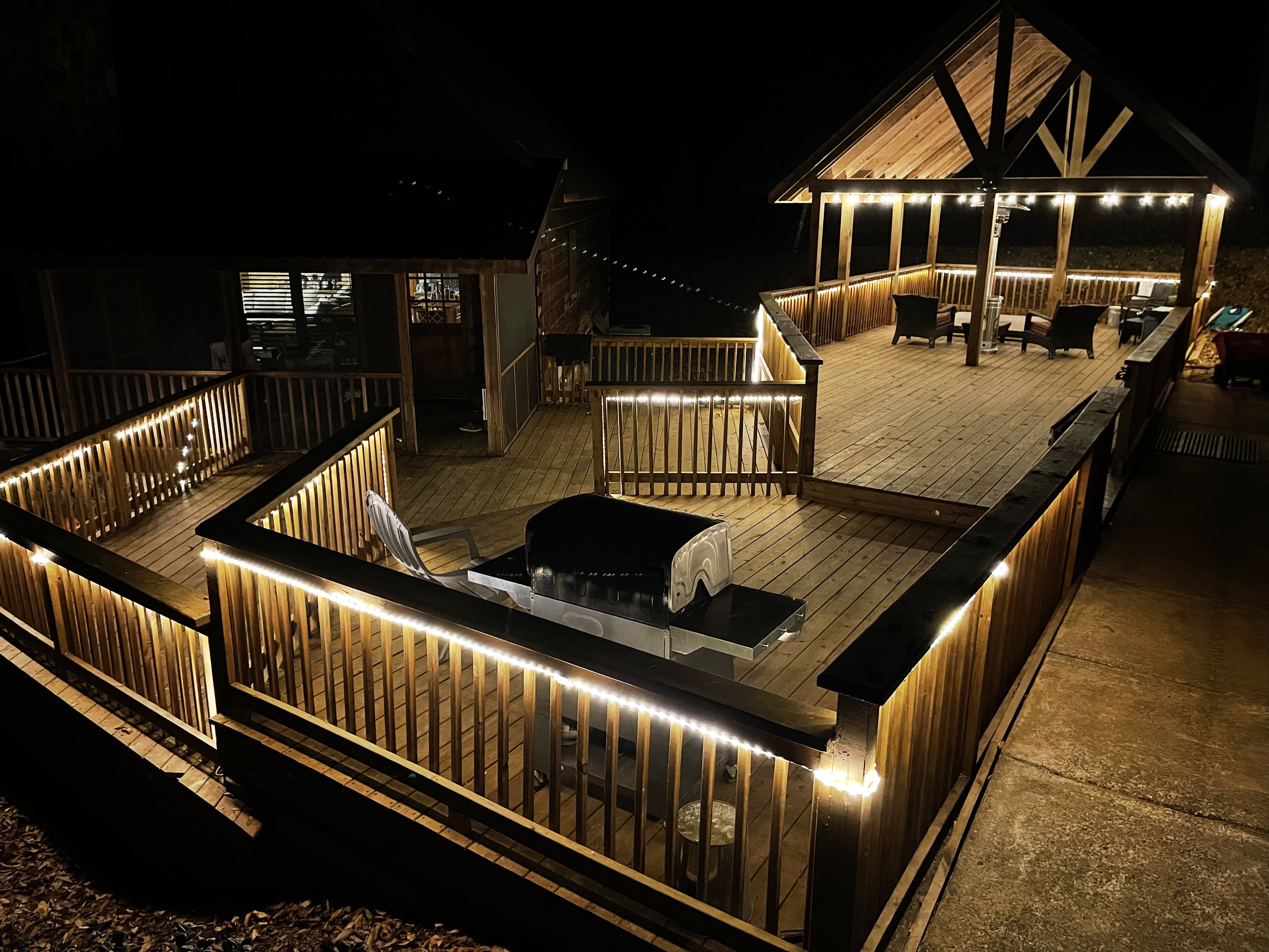 Nighttime deck with grill area, string lights and pavilion in the background